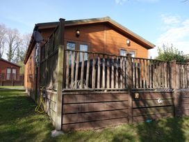 An outdoor view of a cabin with decking and a fenced area at Woodland View 31 - The Hawthorns Finlakes Holiday Park near Chudleigh