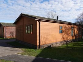 A wooden lodge with windows and a door at Woodland View 31 - The Hawthorns near Finlakes Holiday Park