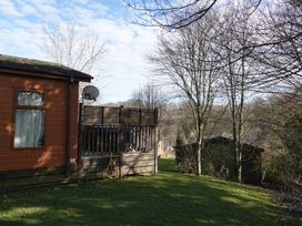 A wooden lodge with a satellite dish and decking at Woodland View 31 - The Hawthorns near Finlakes Holiday Park near Chudleigh
