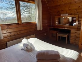A bedroom with a bed, desk, and windows at Tor View, Finlakes Holiday Park near Chudleigh