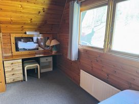A bedroom with a bed, mirror, desk, and window at Tor View Finlakes Holiday Park near Chudleigh