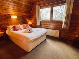 A bedroom with a bed and windows at Tor View Finlakes Holiday Park near Chudleigh