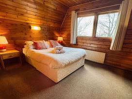 A bedroom with a bed, bedside lamps and a window at Tor View, Finlakes Holiday Park near Chudleigh