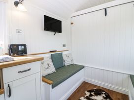 A small seating area with green cushions under a wall-mounted television and a countertop with a toaster at Airlie Burnside near Forfar
