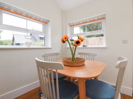 A dining room with a round table and sunflowers at Glendale in Port Isaac