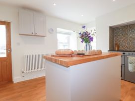 A kitchen with a wooden island and flowers at Glendale in Port Isaac