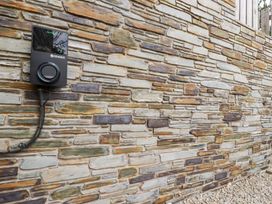 A wall-mounted electric vehicle charger on a stone wall at Glendale in Port Isaac