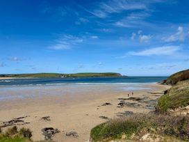 A beach with two people walking along the shore at Glendale in Trelights near Port Isaac
