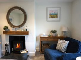 A living room with a fireplace and a blue armchair at Glendale in Trelights near Port Isaac