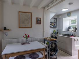 A kitchen with a table and chairs alongside cooking appliances at 1 Aberbeinw Dolwyddelan
