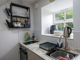 A kitchen with a sink, stove, and shelf at 1 Aberbeinw, Dolwyddelan