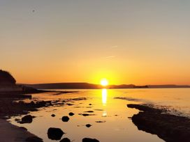 A sunset over water with rocks at The View in Weymouth