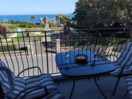 A balcony with a table and chairs overlooking a garden and sea at The View in Weymouth