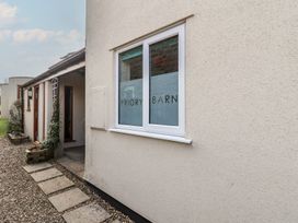 Exterior view of a building with a window displaying Priory Barn and a gravel path leading to a covered entrance at Priory Barn Apartment in Walton near Street