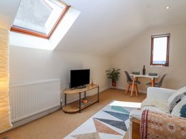 A living room with a television on a stand a small dining table with two chairs and a couch at Priory Barn Apartment Walton near Street