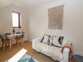 A small dining area with a table set for two and a white sofa with cushions and a throw in a living room at Priory Barn Apartment Walton near Street