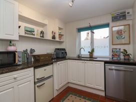 A kitchen with white cabinets brown countertops a small fridge microwave toaster air fryer sink and window at Priory Barn Apartment Walton near Street