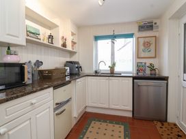 A kitchen with white cabinets a microwave a toaster an air fryer a sink with a window above and a dishwasher at Priory Barn Apartment Walton near Street