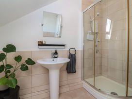 A bathroom with a pedestal sink a mirror a glass shower enclosure and a plant at Priory Barn Apartment Walton near Street