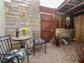 A small outdoor seating area with two chairs and a round table with flowers and a bottle at Priory Barn Apartment Walton near Street