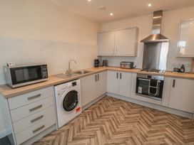 A kitchen with a sink, washing machine, and microwave at The Newborough Apartment 5 Scarborough