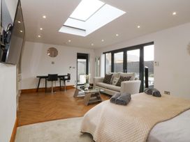 A living room with a sofa, glass table, and a dining table at Lodge in Llangefni