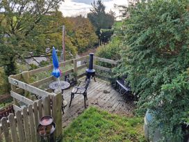 A garden with a deck, table, and chairs at Golygfa Abergele