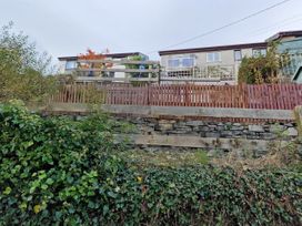 A garden with a stone wall and a wooden fence at Golygfa in Abergele