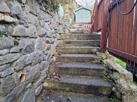 Stone steps leading up to a wooden fence and a shed at Golygfa Abergele