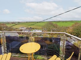 A balcony with a table and chairs overlooking fields at Golygfa in Pandy Tudur near Llanrwst