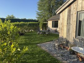 A garden with green grass a wooden house metal outdoor table and chairs a wooden bench and a bathtub at Wayside Lodge in Blackpool