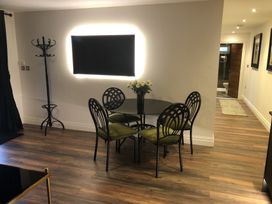 A dining area with a round glass table and four chairs with green cushions at Wayside Lodge in Blackpool