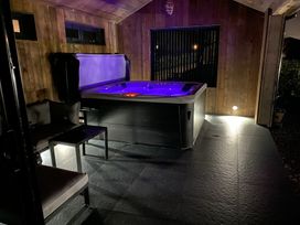 A covered outdoor area with a lit hot tub a small table and chairs at Wayside Lodge in Blackpool