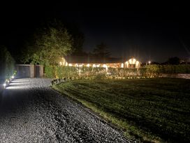 A lit house with a gravel driveway a large lawn and trees at night at Wayside Lodge in Blackpool