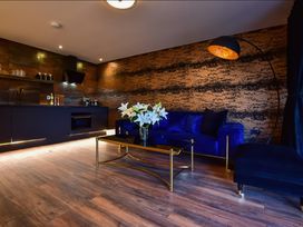 A living area with a blue sofa a gold and black coffee table with white flowers and a kitchen area at Wayside Lodge in Blackpool