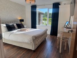A bedroom with a bed two black pillows a desk and a window with dark curtains at Wayside Lodge in Blackpool