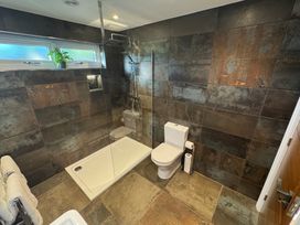 A bathroom with a walk-in shower toilet towel rack and a small plant on the window at Wayside Lodge in Blackpool