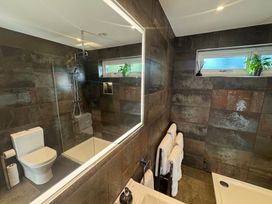 A bathroom with a toilet shower illuminated mirror towels and plants at Wayside Lodge in Blackpool