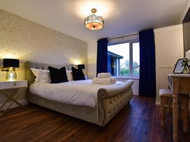 A bedroom with a large bed and two rolled towels on it bedside tables with lamps a window with dark curtains and a dressing table with a mirror at Wayside Lodge in Blackpool