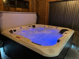 An indoor hot tub with blue lights and a glass of wine on the edge at Wayside Lodge in Blackpool