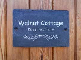A slate sign with the text Walnut Cottage Pen y Parc Farm mounted on wooden boards at Walnut Cottage in Halkyn