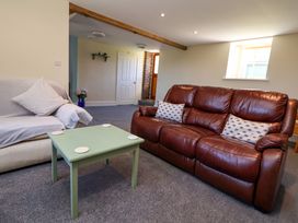 A living room with a brown leather sofa a beige sofa covered with a cloth and a green coffee table at Walnut Cottage in Halkyn