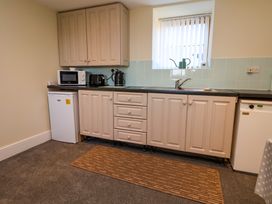 A kitchen with beige cabinets, a microwave, toaster, kettle, mini fridge, sink, and a window at Walnut Cottage in Halkyn
