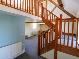 An interior view of a room with wooden stairs and railings leading to a loft area at Walnut Cottage in Halkyn