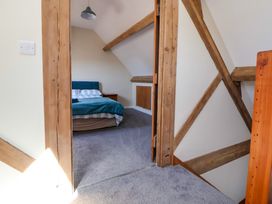 A bedroom with a bed and bedside table visible through a doorway with exposed wooden beams at Walnut Cottage in Halkyn