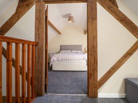 A bedroom with a bed and bedside tables viewed through a wooden doorway at Walnut Cottage in Halkyn