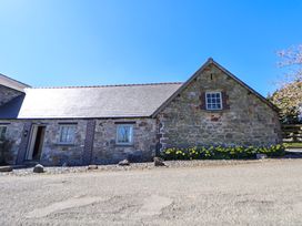 Stone building with three windows and yellow flowers along the base at Walnut Cottage in Halkyn