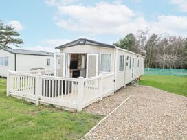 A static caravan with an open patio door and railing on a gravel driveway surrounded by grass at 75 Foxburrow Hang in Fritton