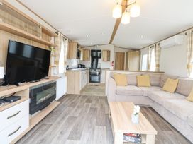 A living room with a sectional sofa and a coffee table next to a kitchen area at 75 Foxburrow Hang in Fritton