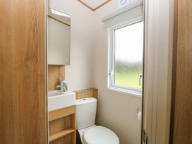 A small bathroom with a toilet sink mirror and window at 75 Foxburrow Hang in Fritton